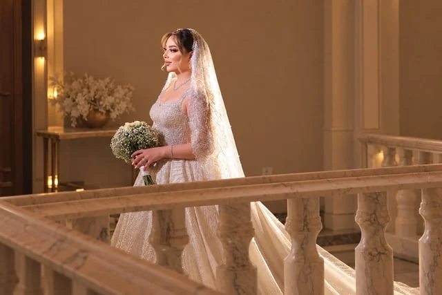 Bride holding a bouquet beside a warm stone balustrade