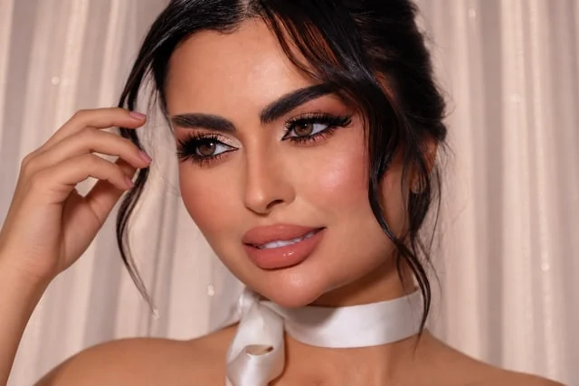 Defined eyes and glossy peach lips with a satin neck ribbon