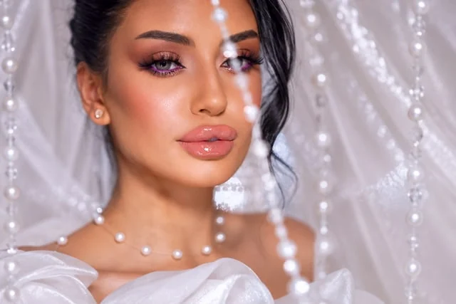 Violet eyeliner and glossy lips behind delicate pearl strands
